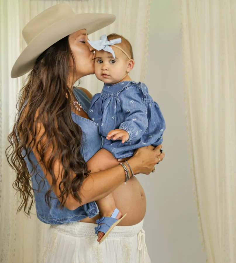 Mother kissing her baby girl in matching denim