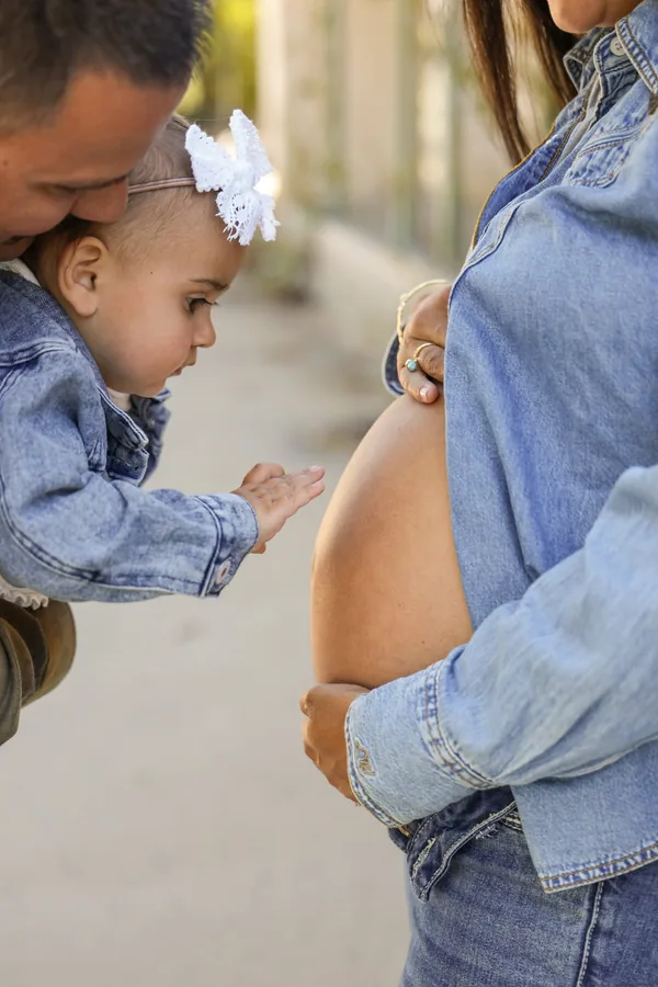 Big sister reaching for her mother's baby bump